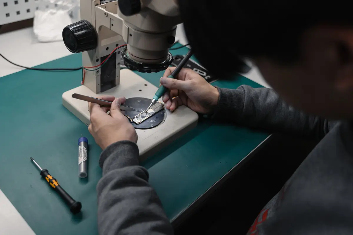 Técnico inspeccionando y reparando una placa bajo microscopio